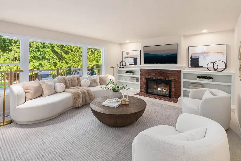 Family room with a brick fireplace, built-in shelving and windows onto the back deck