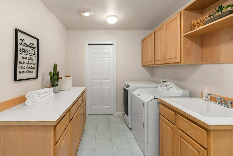 Laundry room with a folding counter, utility sink, cabinets and a closet