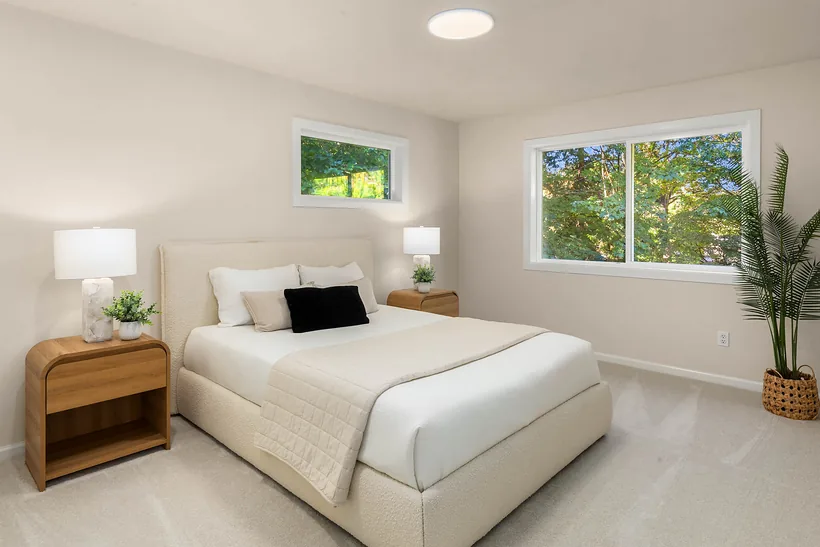 Main-floor office staged as a bedroom with tree views