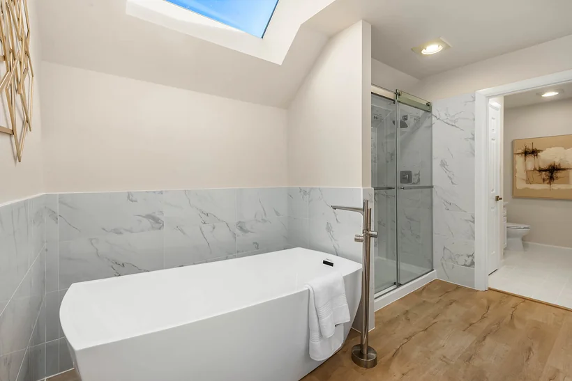 Primary bath with a freestanding soaking tub, skylight and glass-enclosed shower